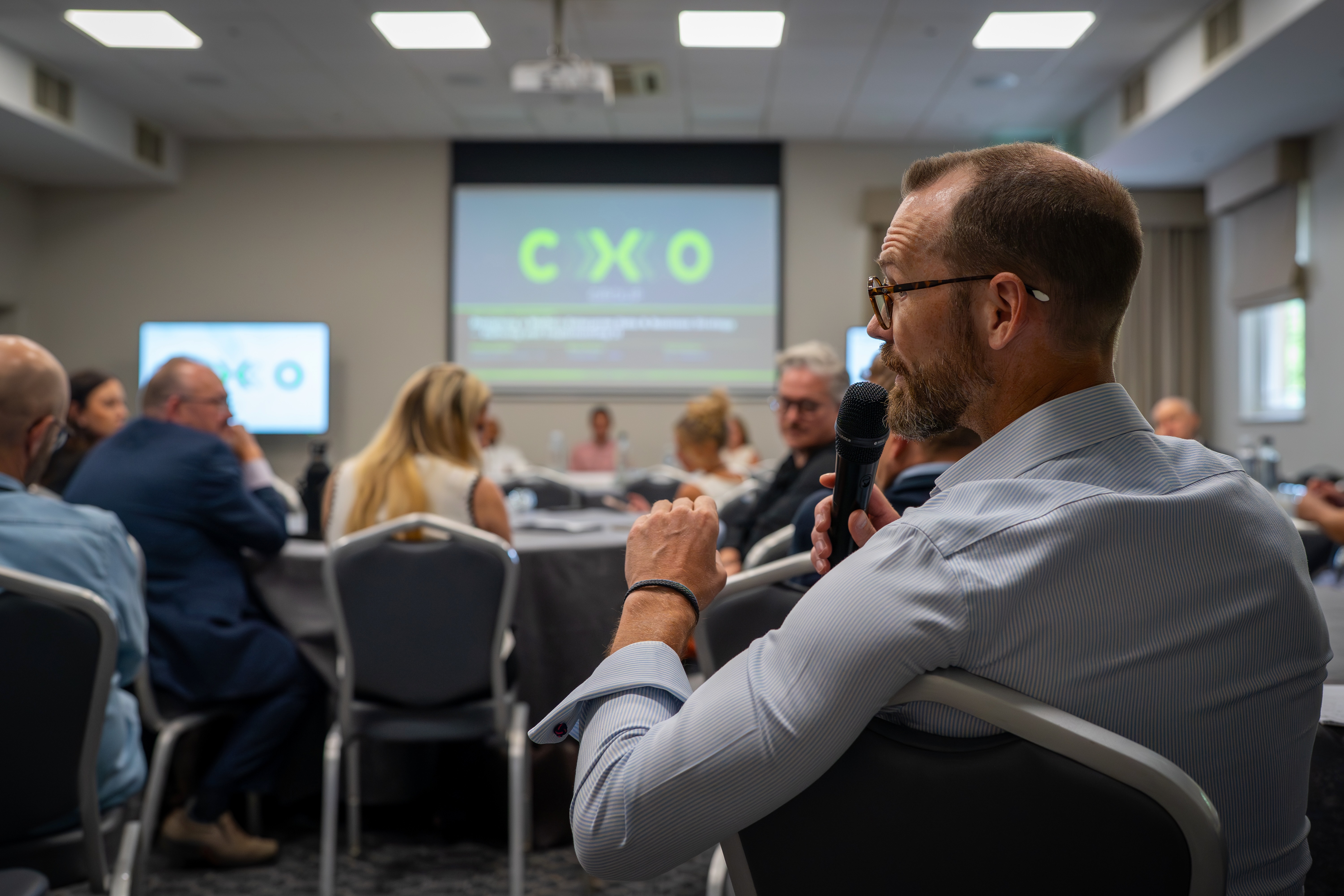Brendan Ellis leading a CXO discussion with a microphone